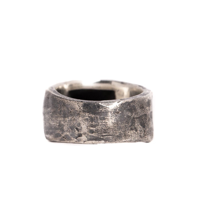 May include: A silver ring with a textured, hammered finish. The ring is wide and has a slightly rounded shape.