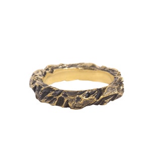 May include: A gold ring with a textured, rough surface. The ring is made to look like a piece of rock.