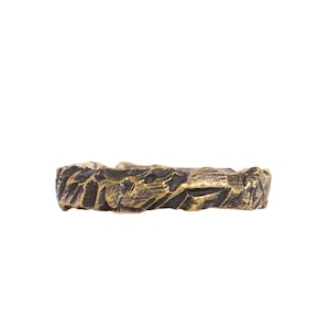 May include: A gold and black textured ring with a rough, organic design.