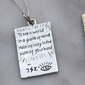 May include: Silver necklace with a rectangular pendant that reads "To see a world in a grain of sand Hold infinity in the palm of your hand". The pendant also has a small eye symbol and the number 925.