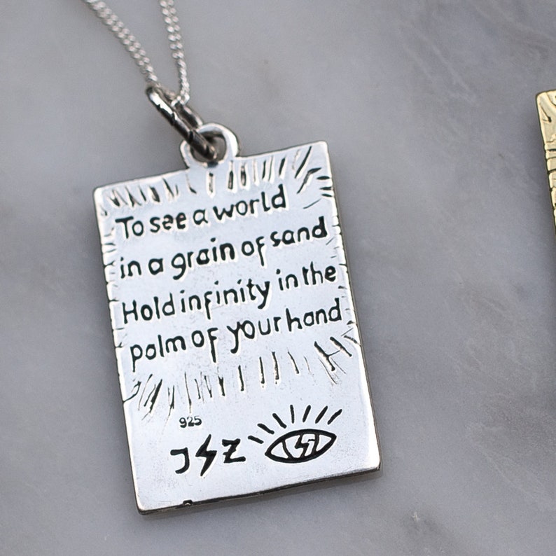 May include: Silver necklace with a rectangular pendant that reads "To see a world in a grain of sand Hold infinity in the palm of your hand". The pendant also has a small eye symbol and the number 925.