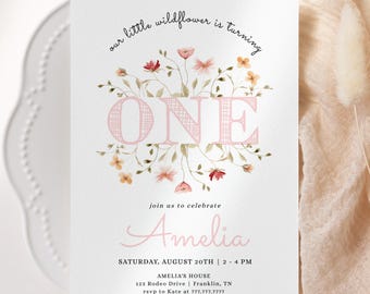 May include: A white invitation card featuring the text "our little wildflower is turning ONE" with floral illustrations. The card includes the name "Amelia", event details, and RSVP information for a first birthday celebration.