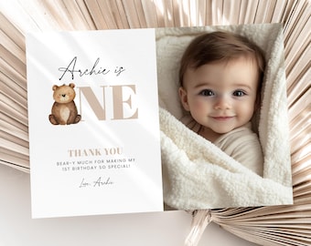 May include: A baby's first birthday card with a photo and text. The card reads "Archie is ONE" with a teddy bear illustration. The text "THANK YOU BEAR-Y MUCH FOR MAKING MY 1ST BIRTHDAY SO SPECIAL!" is also included.
