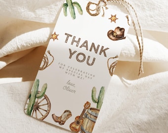 May include: A rectangular gift tag with a cowboy theme. The tag features the words "THANK YOU" in brown text, along with illustrations of cacti, a cowboy hat, and a guitar. The tag is tied with a natural twine.