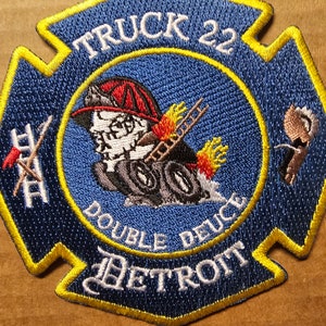 May include: A blue and yellow firefighter patch with the text "TRUCK 22 DOUBLE DEUCE DETROIT" and a cartoon image of a firefighter.
