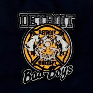 May include: A yellow and black embroidered patch with the text "Detroit Fire Dept. Bad Boys" and a skull with horns in the center.
