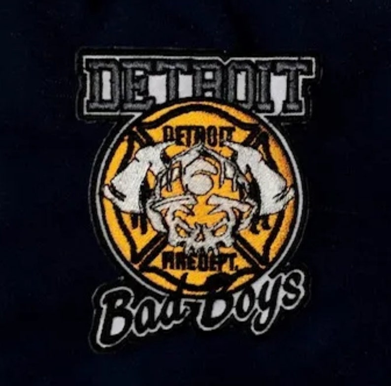 May include: A yellow and black embroidered patch with the text "Detroit Fire Dept. Bad Boys" and a skull with horns in the center.