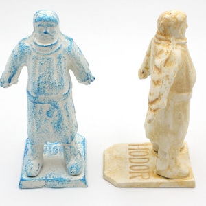 May include: Two painted figurines of a man standing on a base. The figurine on the left is painted blue and white. The figurine on the right is painted white and brown. The base of the figurine on the right has the word "HODOR" written on it.