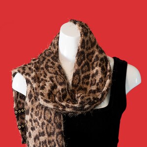 Schal in einem braunen und braunen Leoparden-Print. Die Enden verfügen über schwarzes und goldenes Tüllband.