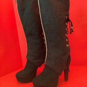 Boot covers made with a black brocade fabric and a satin lining. Features gold chain down center front, and brass skull beads on ties.