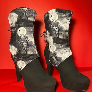 May include: Black platform boots with a black and white fabric boot cuff featuring a moon, trees, and birds. The fabric cuff is folded down to show the design.