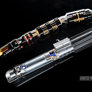 May include: Two disassembled lightsabers, one with a gold and black hilt and the other with a silver hilt. The lightsabers are on a black surface. The text "SINISTER PROPZ" is visible in the lower right corner of the image.