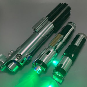 May include: Three silver lightsaber toys with green lights. The lightsabers are made of metal and plastic and have a realistic design.