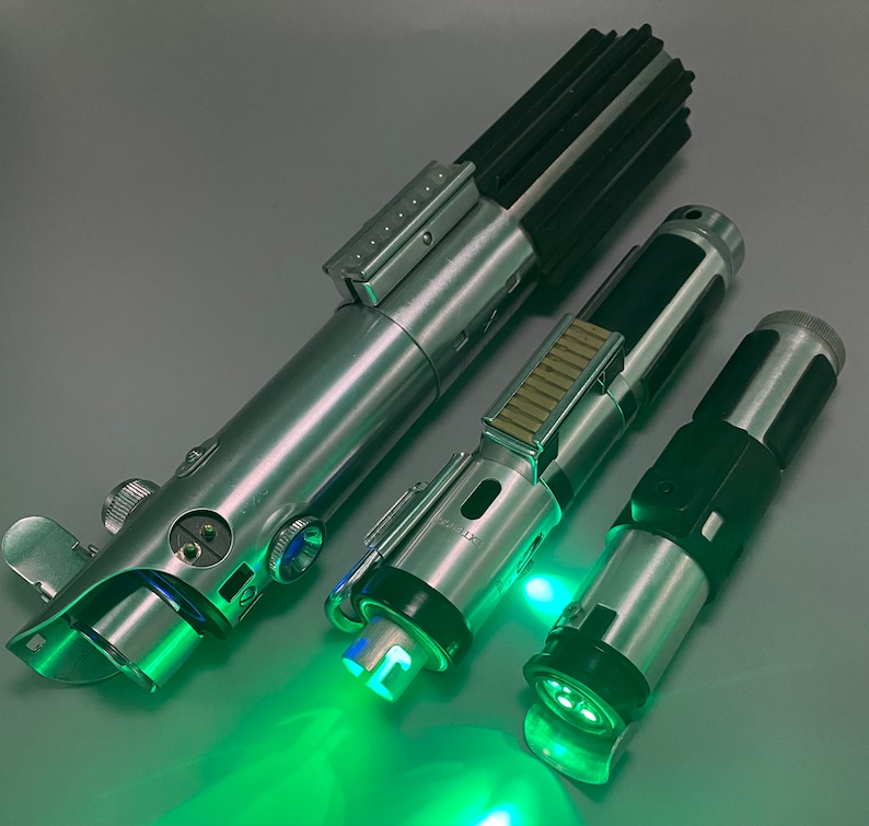 May include: Three silver lightsaber toys with green lights. The lightsabers are made of metal and plastic and have a realistic design.