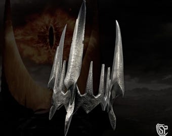 May include: A silver crown with sharp, pointed spikes. The crown is made of metal and has a dark, aged finish.