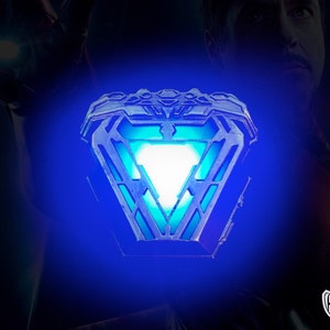 May include: A blue and silver Iron Man Arc Reactor replica with a glowing white light in the center. The replica is a popular collectible for fans of the Marvel Cinematic Universe.