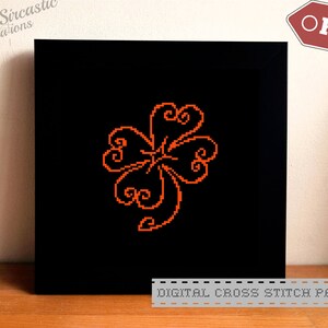 May include: Digital cross stitch pattern featuring a stylized orange four-leaf clover on a black background. The pattern is labeled "DIGITAL CROSS STITCH PATTERN".