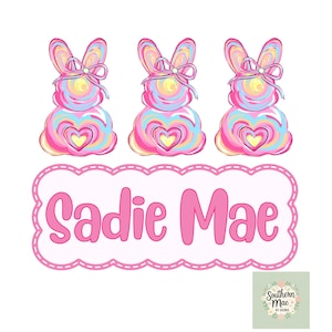 Op de afbeelding: Een digitale illustratie met drie kleurrijke konijnvormige lolly's met hartvormige centra en strikken. Daaronder staat een roze banner met geschulpte randen met de naam "Sadie Mae" in een speels lettertype. Klein logo rechtsonder.