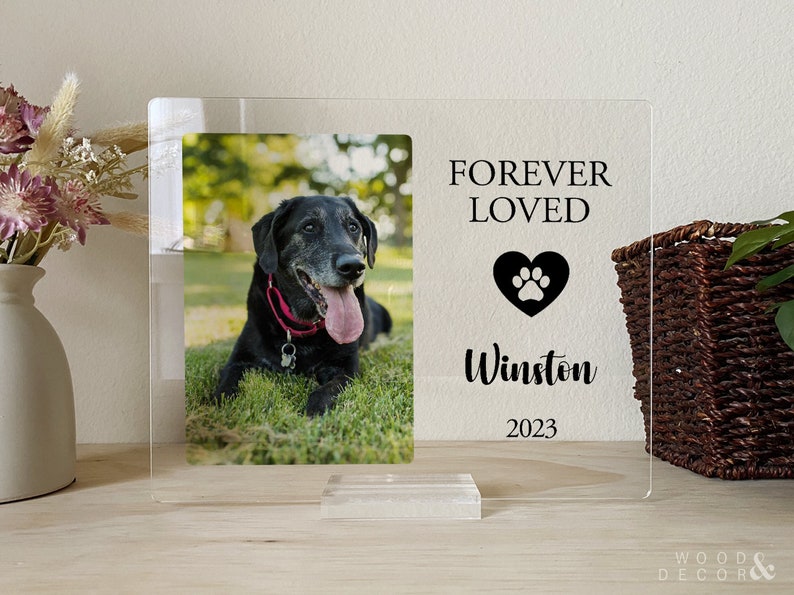 Peut inclure: Un cadre photo en acrylique transparent avec une photo en noir et blanc d'un chien. Le cadre porte le texte "FOREVER LOVED" avec un c&oelig;ur et une empreinte de patte, le nom "Winston" et l'ann&eacute;e "2023".