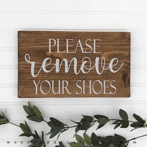 May include: A rustic wooden sign with the text "PLEASE remove YOUR SHOES" in white lettering.