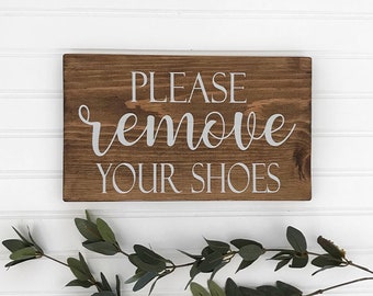 May include: A rustic wooden sign with the text "PLEASE remove YOUR SHOES" in white lettering.