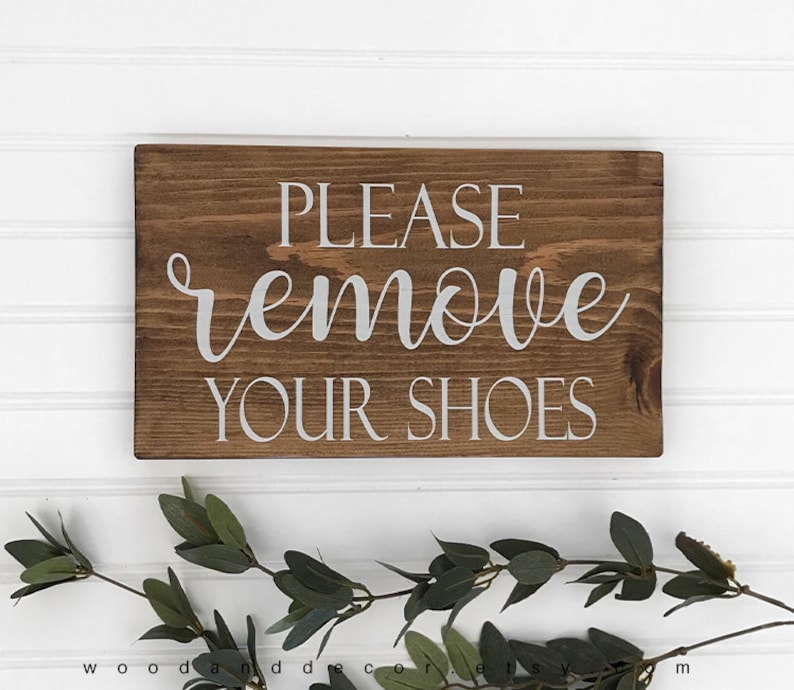 May include: A rustic wooden sign with the text "PLEASE remove YOUR SHOES" in white lettering.