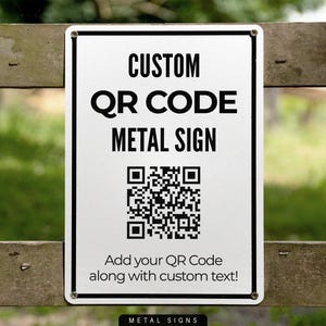 May include: A rectangular metal sign with the text "CUSTOM QR CODE METAL SIGN" in black. Below the text is a QR code. The sign also includes the text "Add your QR Code along with custom text!"