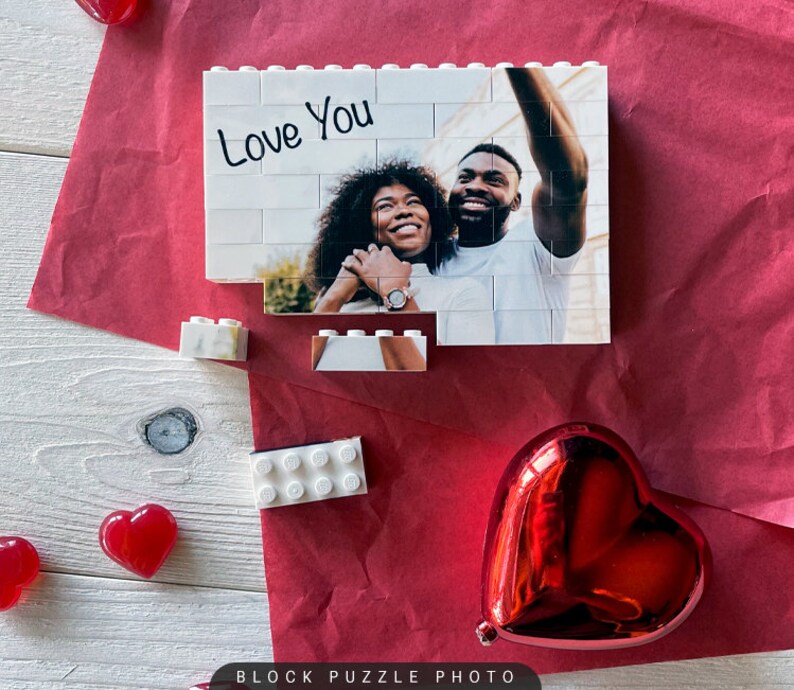 Puede incluir: Un rompecabezas de bloques blancos con una foto de una pareja tomando una selfie. El rompecabezas est&aacute; parcialmente ensamblado y las palabras "Love You" est&aacute;n escritas en la parte superior del rompecabezas.