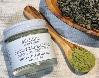 May include: A small glass jar with a white lid containing a green face whip. The jar is labeled "WILD ELIXIRS RAW SKINCARE ESSENTIALS Antioxidant Face Whip MATCHA GREEN TEA MARULA & GREEN TEE SEED OILS NT.WT. 1 FL OZ/28 ML".