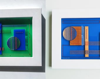 May include: Two framed abstract art pieces. The first piece features a green background with blue and red geometric shapes. The second piece features a blue background with a brown geometric shape and a circle with red and blue lines.