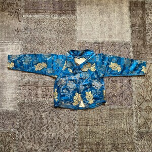 May include: A blue and gold brocade jacket with a mandarin collar and floral pattern.