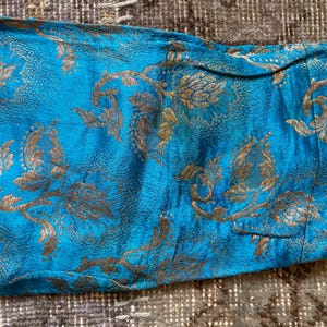 Puede incluir: Primer plano de una tela azul con un patr&oacute;n floral dorado. La tela tiene una apariencia texturizada, similar al brocado.