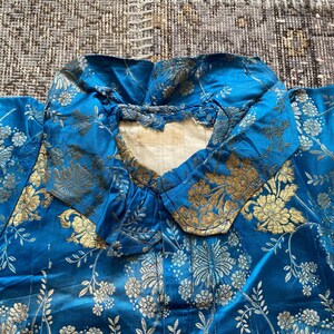 May include: A blue silk robe with a gold floral pattern. The robe has a large collar and is made of a luxurious fabric.