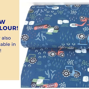 Op de afbeelding: Blauwe stof met een herhalend patroon van tractoren die hooibalen vervoeren. De tractoren zijn rood, blauw en groen. De achtergrond is donkerblauw met kleine witte bloemen en groen gras.