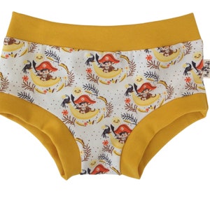 May include: Yellow and white cotton underwear with a print of monkeys wearing pirate hats and riding on crescent moons. The underwear has a yellow waistband and a Hopidi label.