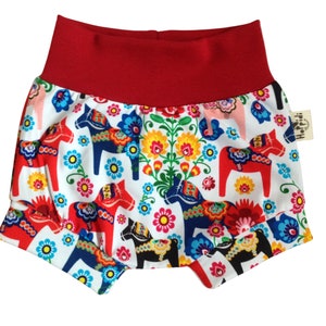 May include: Red and white baby bloomers with a pattern of colorful Swedish Dala horses and flowers.