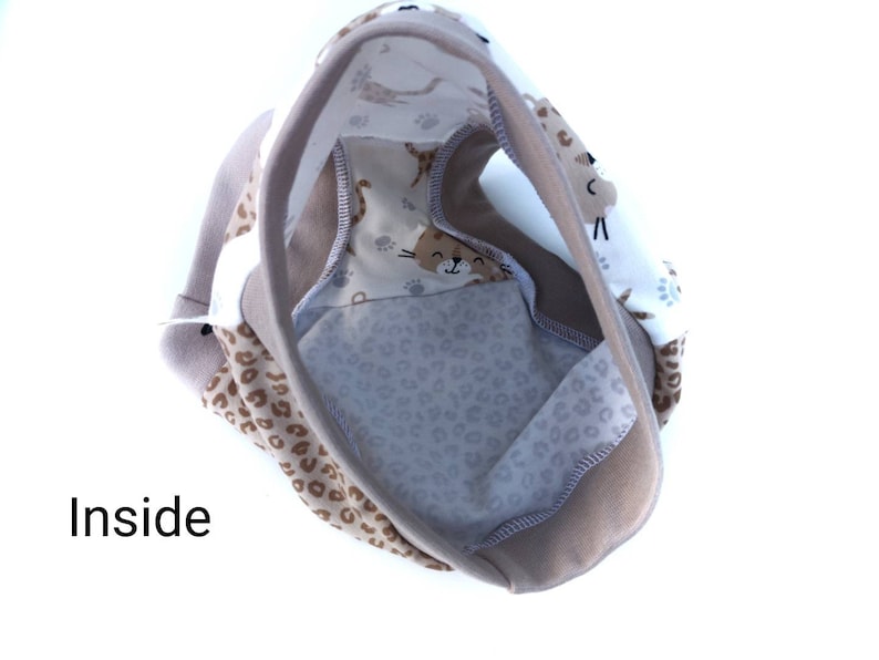 Pode incluir: Roupa interior com um painel de tecido branco com um padr&atilde;o castanho de caras de gato e pegadas, contrastado com tecido de estampado de leopardo bege. A pe&ccedil;a tem bordas bege s&oacute;lidas e a palavra Inside impressa em preto.