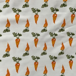 Puede incluir: Tela blanca con un patrón repetido de zanahorias naranjas con hojas verdes.