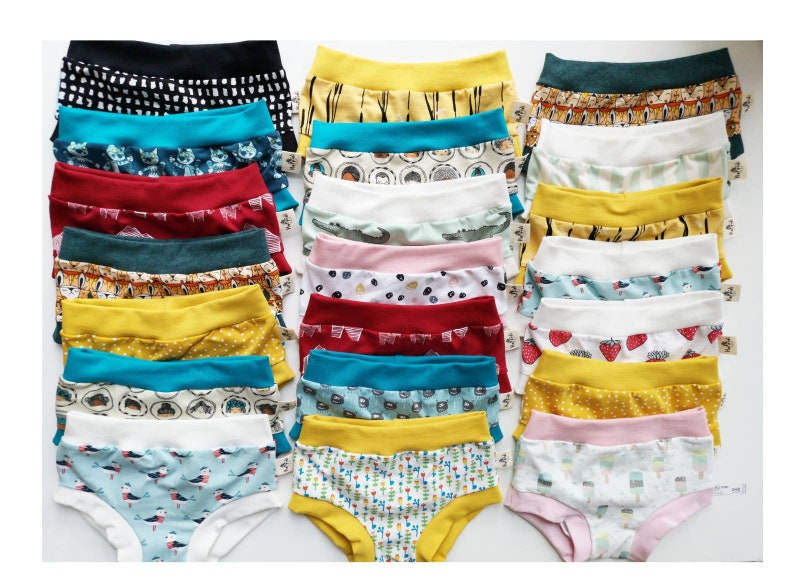 Pode incluir: Uma cole&ccedil;&atilde;o de vinte e uma pe&ccedil;as de roupa interior infantil dispostas em tr&ecirc;s colunas. Cada pe&ccedil;a apresenta um c&oacute;s el&aacute;stico largo de cor s&oacute;lida e uma variedade de padr&otilde;es coloridos, incluindo animais, frutas, formas geom&eacute;tricas e alimentos.