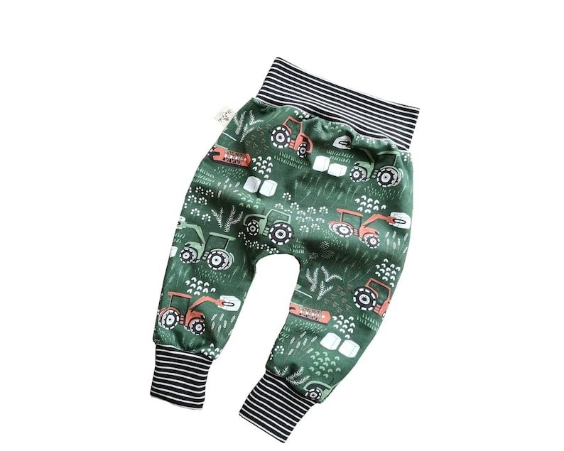 Op de afbeelding: Groene baby leggings met een tractorprint. De leggings hebben zwart-witte strepen aan de tailleband en de boorden.