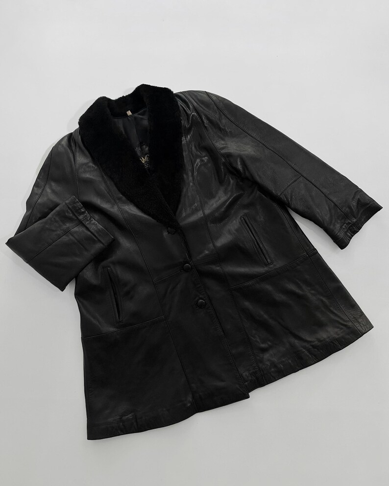May include: Black leather coat with a faux fur collar. The coat has a button-up front, two front pockets, and long sleeves. The coat is a classic style, suitable for cooler weather.