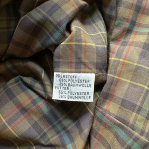 May include: Close-up of a fabric label with the text "Oberstoff: 65% Polyester 35% Baumwolle Futter: 65% Polyester 35% Baumwolle".
