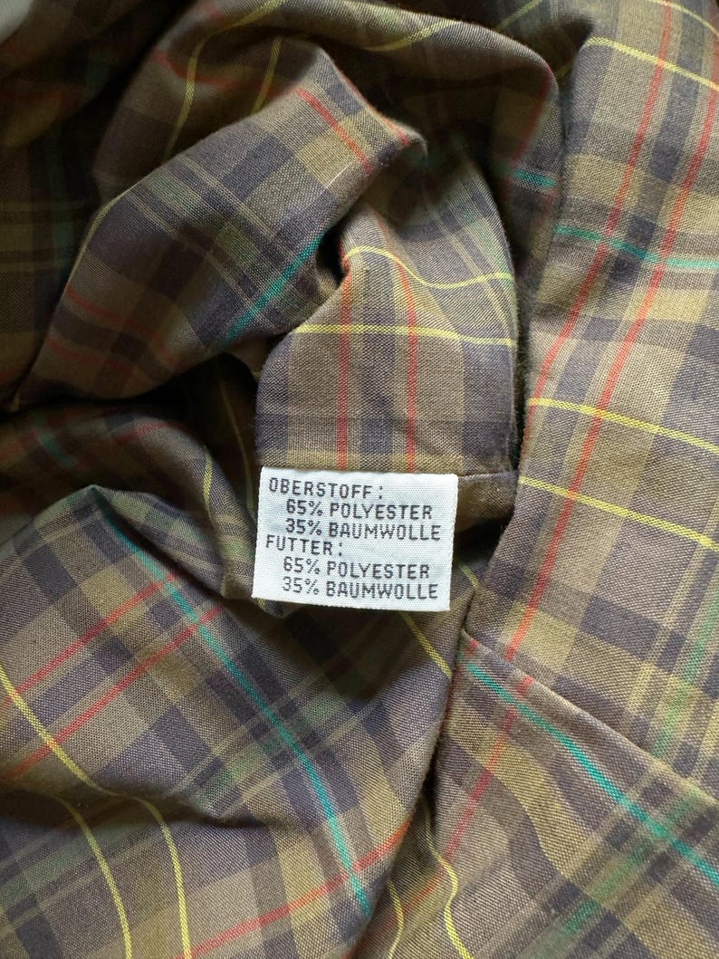 May include: Close-up of a fabric label with the text "Oberstoff: 65% Polyester 35% Baumwolle Futter: 65% Polyester 35% Baumwolle".
