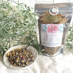 May include: A silver pouch with a label that reads "Spring Equinox Simmer Pot" and lists the ingredients: chamomile, rose, orange, allspice, lemon, lavender, pine, calendula, blue cornflower, mint, bay laurel. The pouch is filled with dried herbs and flowers.