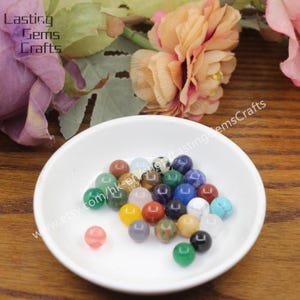 May include: A white bowl filled with a variety of small, round, colorful gemstone beads. The beads are approximately 6mm in diameter and are made of natural stones such as amethyst, agate, jasper, and turquoise.