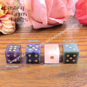 May include: Four gemstone dice in amethyst, sodalite, rose quartz, and moss agate. Each die has gold-colored dots. The image includes text that reads "Lasting Gems Crafts" and "www.etsy.com/hk-en/shop/LastingGemsCrafts".