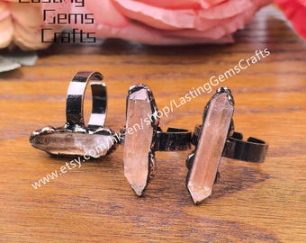 May include: Three adjustable rings with dark metal bands and natural crystal accents. The crystals are light brown and elongated. The rings are displayed on a wooden surface, with the text "Lasting Gems Crafts" visible in the upper left corner.