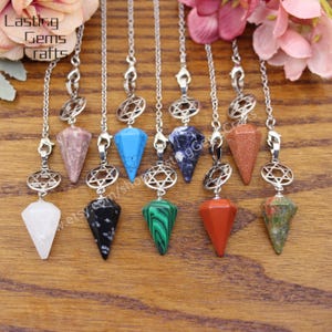 Puede incluir: Un conjunto de diez péndulos de cadena plateada con puntas de cristal de varios colores. Los cristales son: cuarzo transparente, obsidiana negra, malaquita verde, jaspe rojo, arenisca marrón, lapislázuli azul, turquesa, aventurina verde y cuarzo rosa.