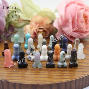 Puede incluir: Una colección de 20 pequeñas figuras de piedra talladas y pulidas en varios colores, incluyendo rosa, azul, verde, blanco, negro y naranja. Las figuras están dispuestas en círculo sobre una superficie de madera. Las figuras miden aproximadamente 2,5 cm de alto.