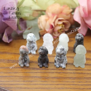Puede incluir: Siete pequeñas figuritas de perro de piedra talladas a mano en varios colores, incluyendo blanco, gris, negro y verde. Las figuritas están sentadas sobre una superficie de madera. www.etsy.com/hk-en/shop/LastingGemsCrafts